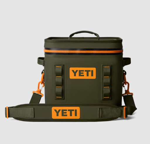 An olive green YETI cooler bag with bright orange accents, including a zipper trim, hardware, and signature orange YETI logos on the front and on the detachable shoulder strap, shown against a light gray background.