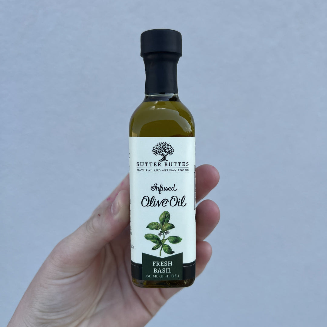 Hand holding a small bottle of Sutter Buttes Fresh Basil infused olive oil