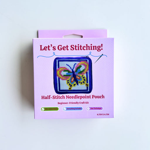A boxed craft kit labeled "Let's Get Stitching!" and "Half-Stitch Needlepoint Pouch" on a plain white background. The package is light purple/lilac with a butterfly needlepoint example shown on the front.