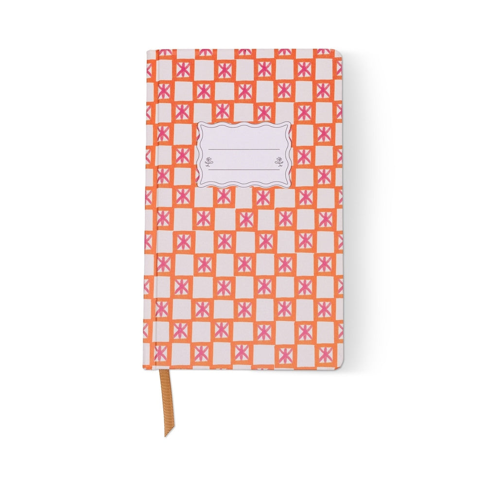 Hardcover notebook by Matilda Goad & Co featuring an orange checkered pattern with pink geometric star motifs, a central scalloped label with floral accents, and a tan ribbon bookmark on a white background