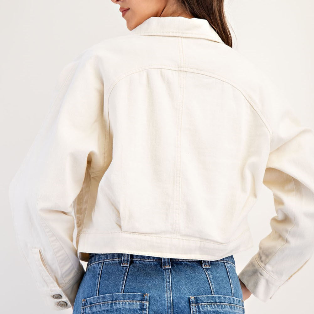 Back view of a cream cropped jacket worn with blue jeans