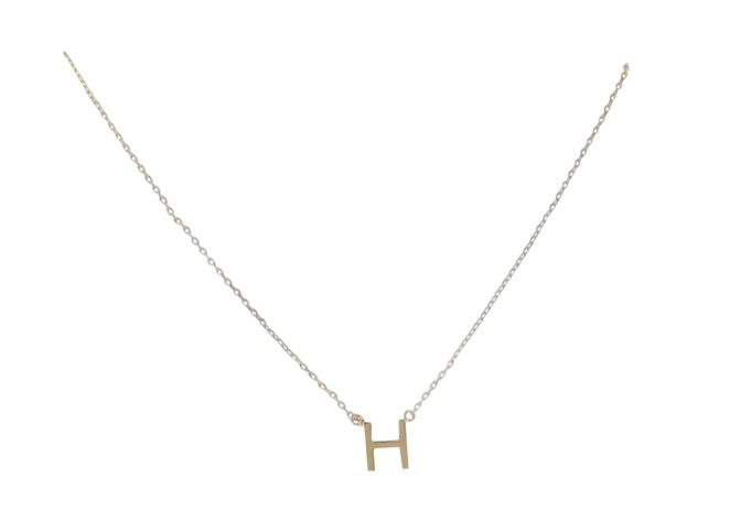 Gold jewelry necklace featuring a minimalist uppercase block letter H pendant suspended from a delicate fine-link chain against a bright white background