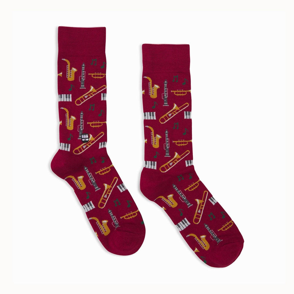 Knitted burgundy crew socks featuring a vibrant pattern of golden saxophones, silver clarinets, and green musical notes displayed on a clean white background