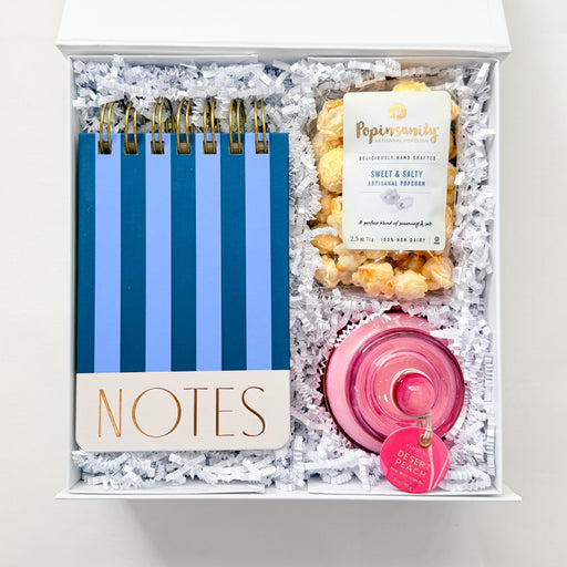 Gift set with notebooks, popcorn, and a candle in a decorative box.