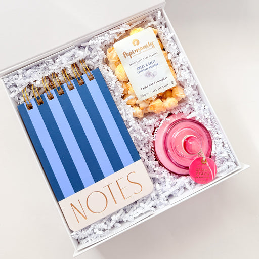 Gift set with notebooks, candles, and a bow on a white background