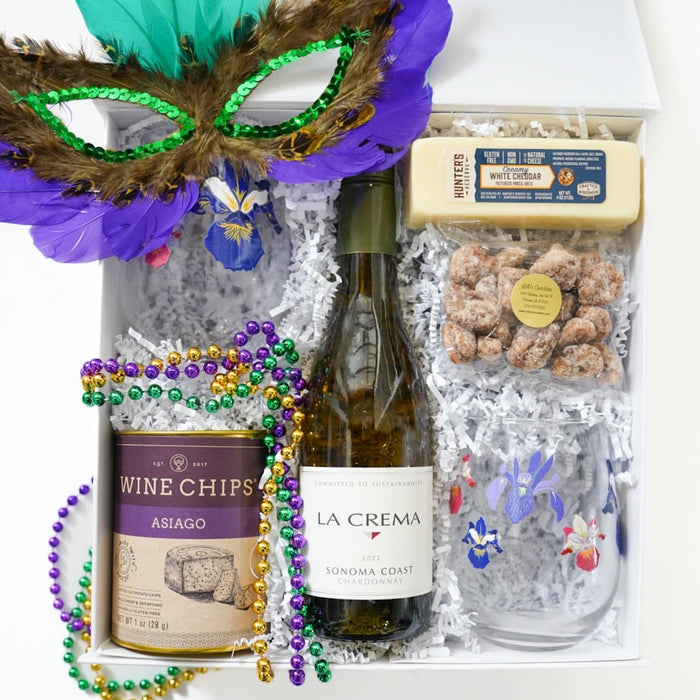Gift basket with wine, cheese, and Mardi Gras-themed items on a white background