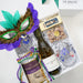 Gift basket with wine, snacks, and Mardi Gras mask on a white background