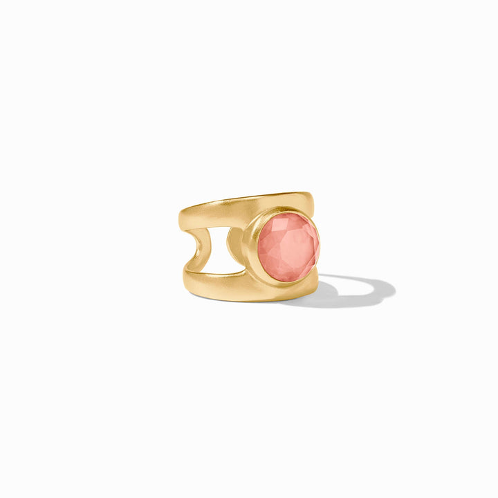 Gold-plated statement ring by Julie Vos showcasing a faceted rose-colored gemstone set within a brushed matte gold frame and a wide split-shank band on a minimalist white surface