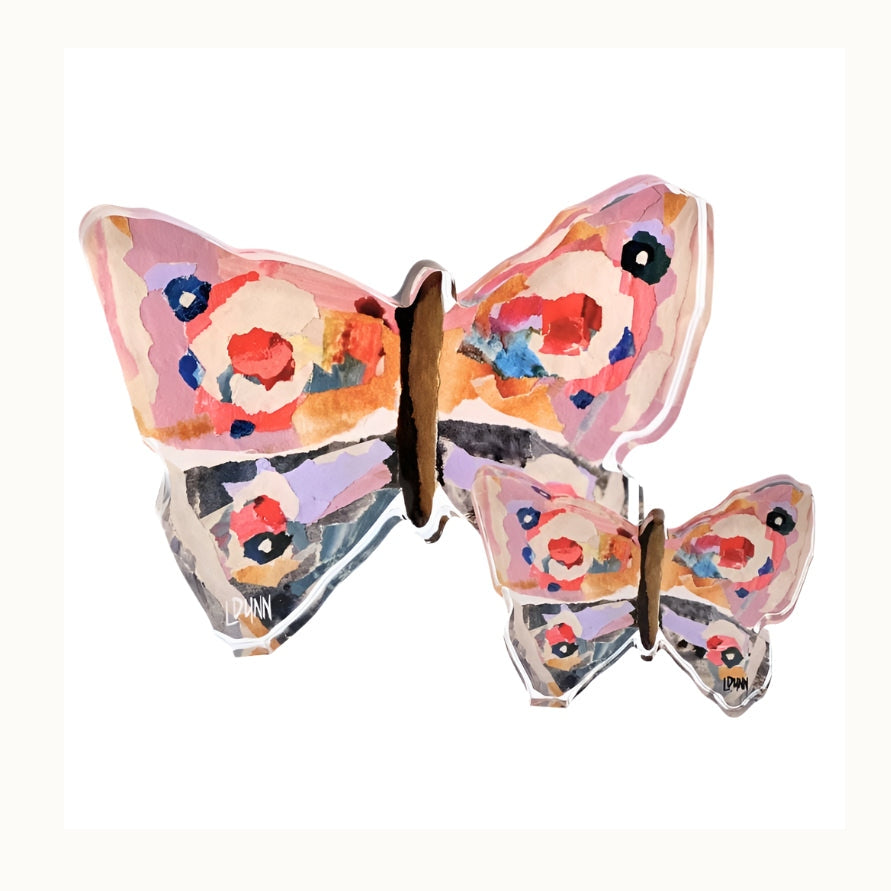Mixed media acrylic block art by L. Dunn featuring two butterflies set against a white background with vibrant pink and orange torn-paper collage patterns and thick transparent polished edges