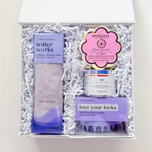 Set of hair care products including a bottle, a jar, and a brush in a decorative box on a white background.