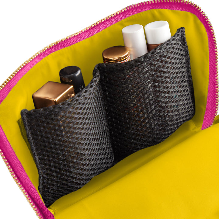 Product photograph of the interior of an open cosmetic bag featuring two black mesh storage pockets, a vibrant yellow lining, and a fuchsia pink exterior with a gold zipper detail