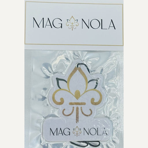 MAG NOLA brand car air freshener featuring a gold and black fleur-de-lis symbol from New Orleans showcased in clear plastic packaging with a white branded header tag