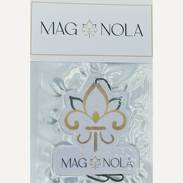 MAG NOLA brand car air freshener featuring a gold and black fleur-de-lis symbol from New Orleans showcased in clear plastic packaging with a white branded header tag