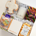 Gift set with a candle, cookies, and snacks in a decorative box.