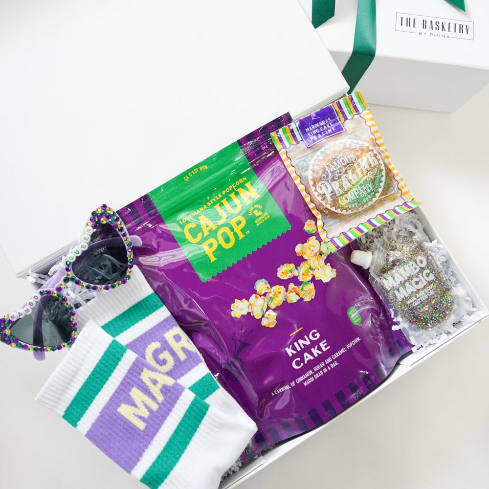 Gift basket with Cajun Pop's King Cake and other items on a white surface