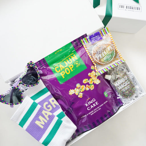 Gift basket with Cajun Pop's King Cake and other items on a white surface