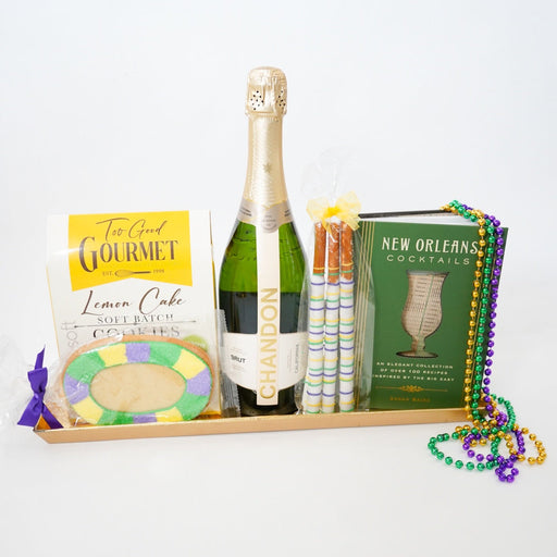 Bottle of champagne on a tray with Mardi Gras-themed items including beads and books.