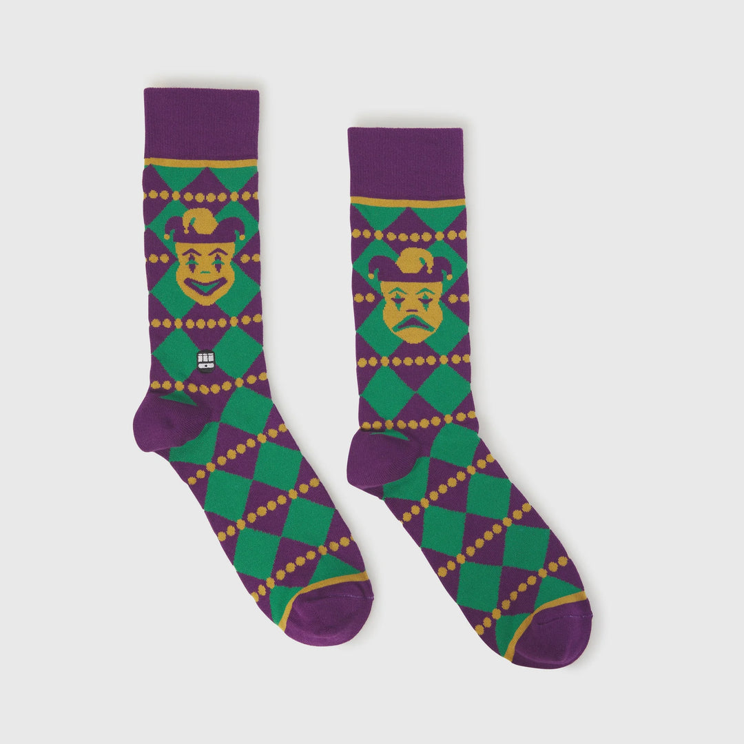 Knitted socks featuring a New Orleans Mardi Gras jester motif and the iconic St. Charles Streetcar landmark displayed on a vibrant purple, green, and gold harlequin pattern with yellow beaded details
