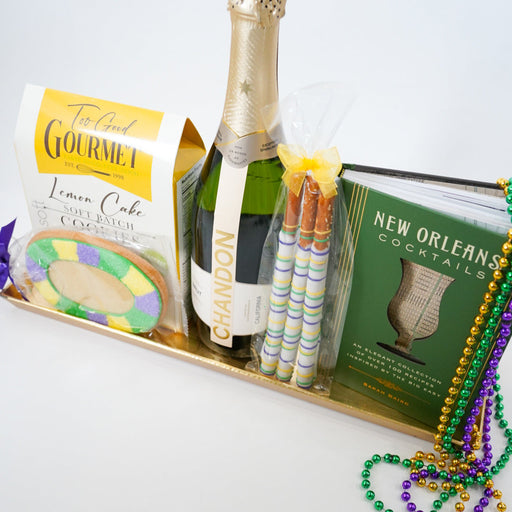Gift basket with champagne, cookies, and Mardi Gras-themed items on a white background