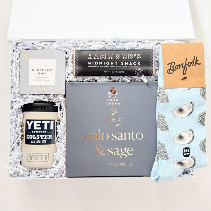 Gift box with various items including a Yeti cup, Palo Santo &amp; Sage box, and other products on a white background.