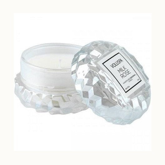 Product photograph of a Voluspa Milk Rose candle featuring a clear faceted glass jar with a geometric jewel-cut pattern and a square white label against a plain white background
