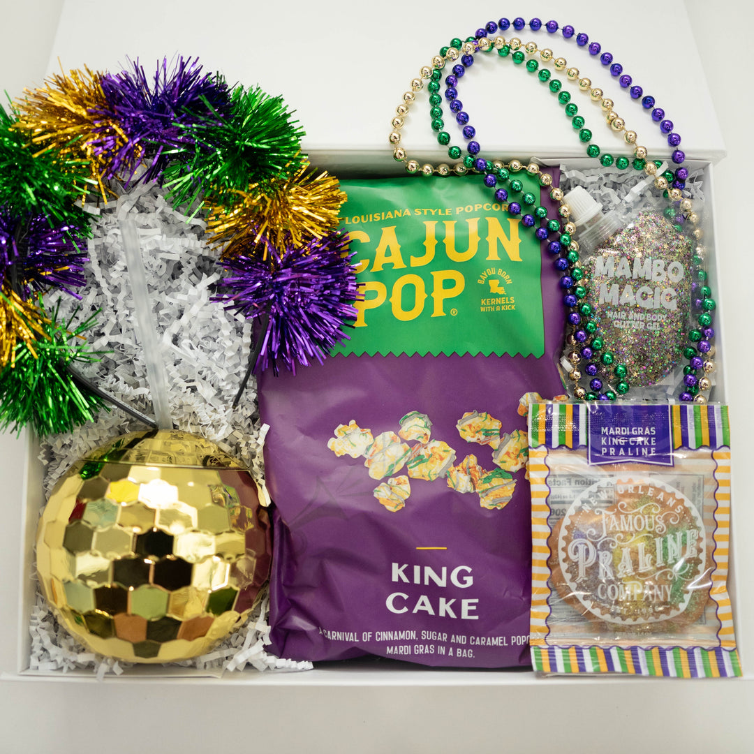 Digital photograph of a New Orleans Mardi Gras gift box featuring Cajun Pop popcorn, a gold disco ball tumbler, and vibrant purple, green, and gold tinsel and beads