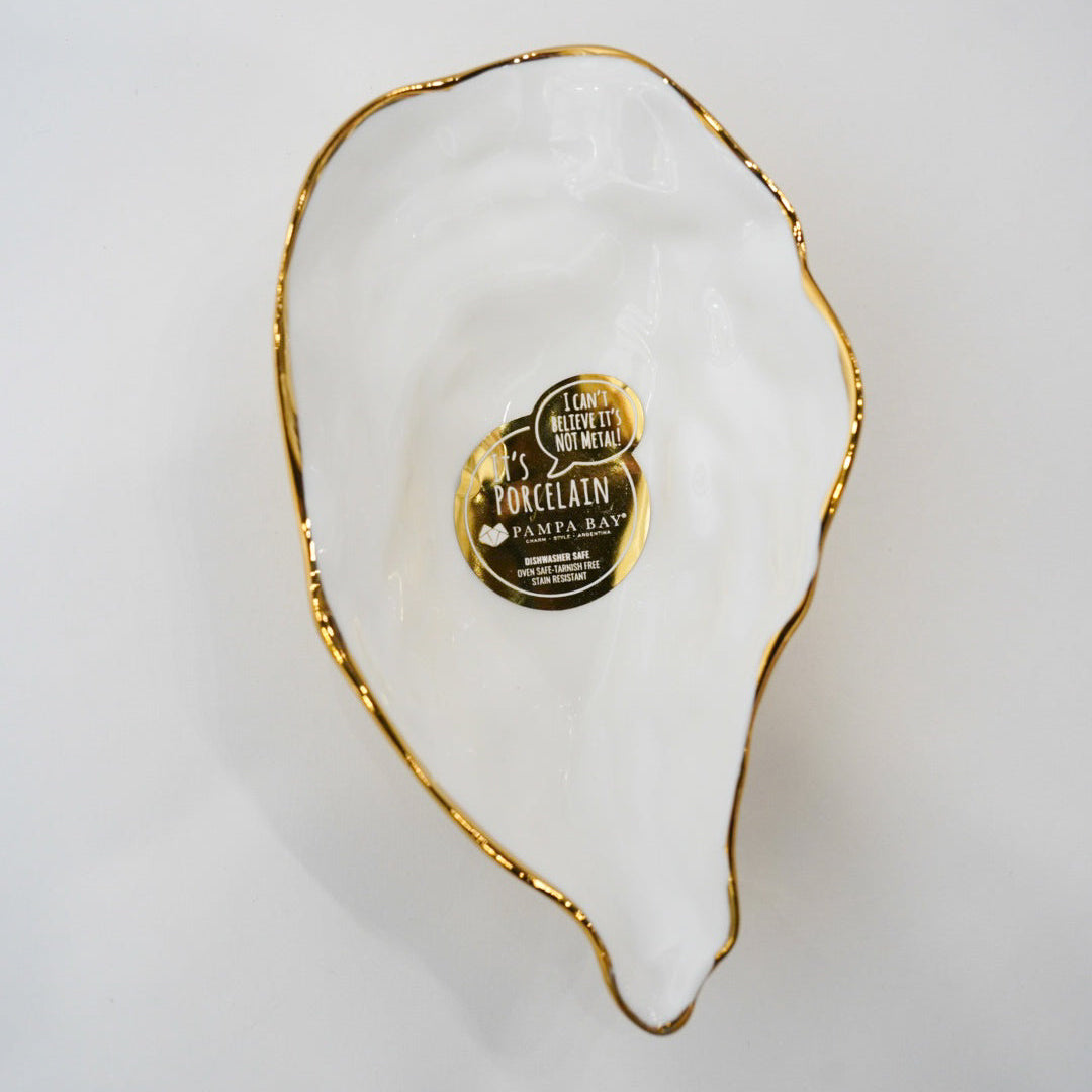 Decorative white dish with gold rim and a label on a light gray background