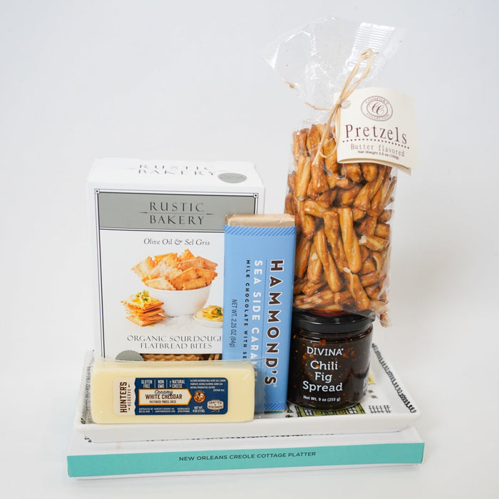 Assorted snacks including pretzels, crackers, and a block of cheese on a white surface.