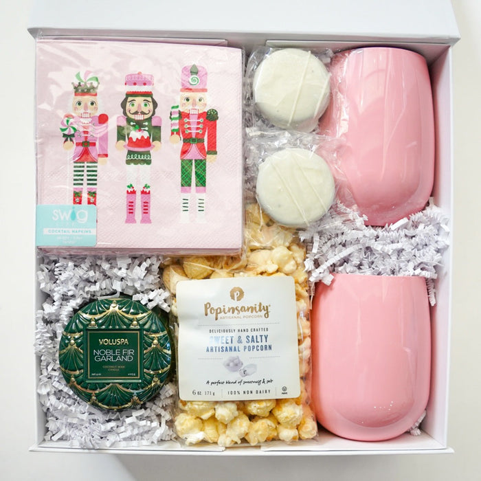 Gift box with pink soaps, popcorn, and decorative items on a white background