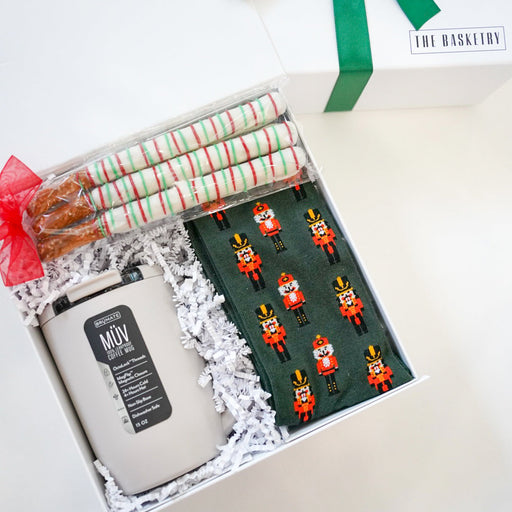 Gift set with a candle, wrapped items, and a green ribbon on a white background