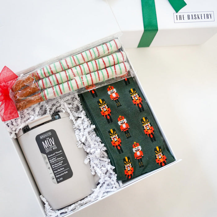 Gift set with a candle, wrapped items, and a green ribbon on a white background