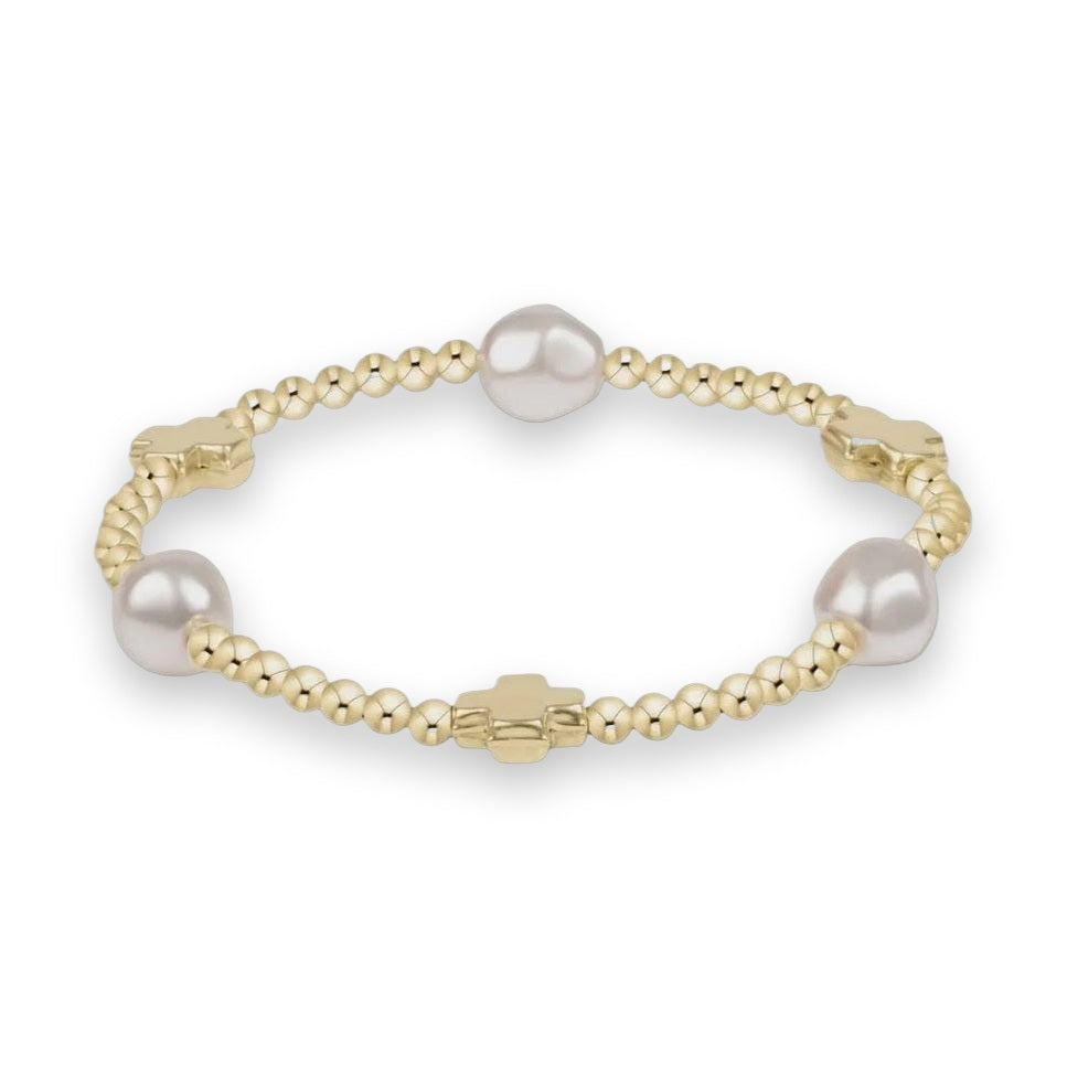 Gold and pearl bracelet by Salvatore Ferragamo featuring a strand of polished yellow gold beads accented by three large white pearls and three iconic signature cross charms on a neutral background