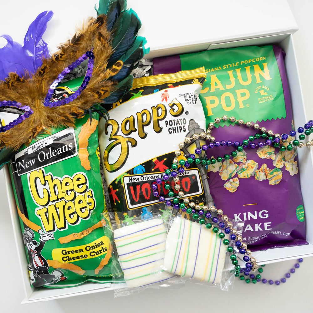 Digital photograph of a New Orleans Mardi Gras gift box featuring Zapp's Voodoo potato chips and Elmer's CheeWees adorned with a flamboyant feathered mask and shimmering metallic purple and gold beads