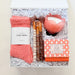 Gift set with coral socks, candle, and other items in a box on a white background