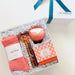 Gift set with pink socks, candles, and other items in a decorative box on a white background