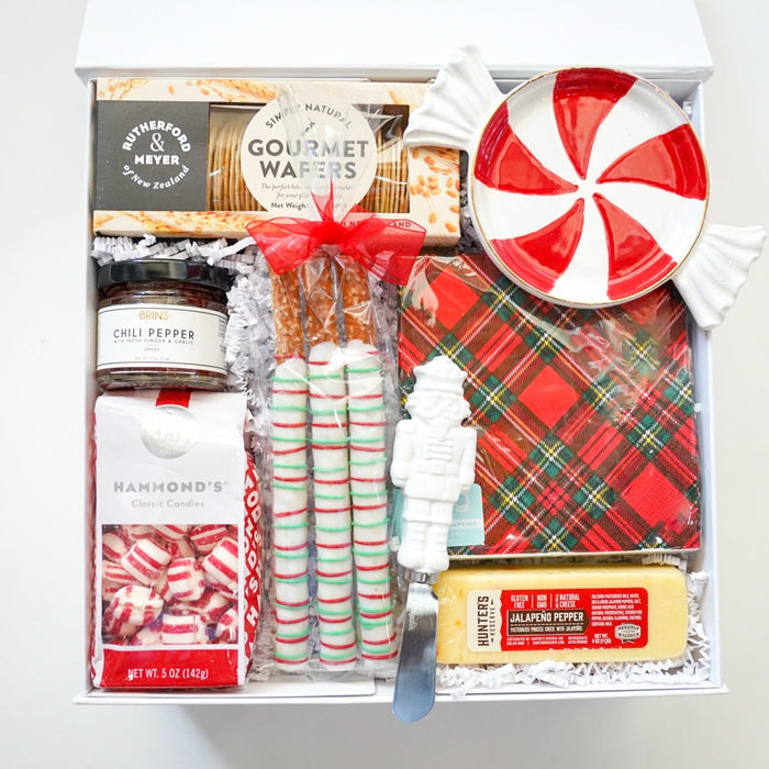 Assorted holiday treats including peppermints, candy canes, and a plaid bag in a gift box.