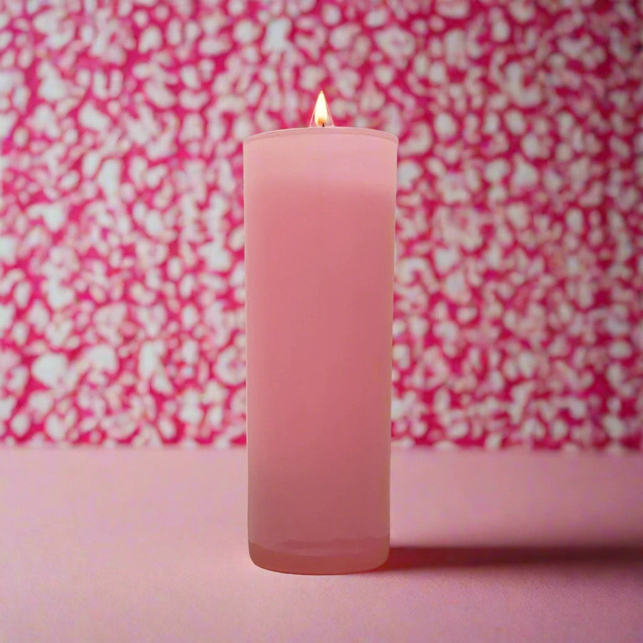 Lit pink votive candle in front of a pink and white patterned background