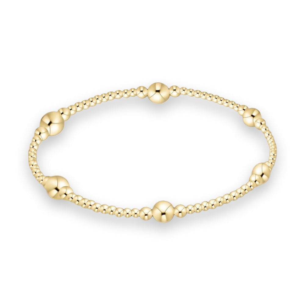 14k gold filled beaded bracelet by Erimish centered on a white background featuring small polished spheres and five larger focal gold beads with a high-shine reflective finish