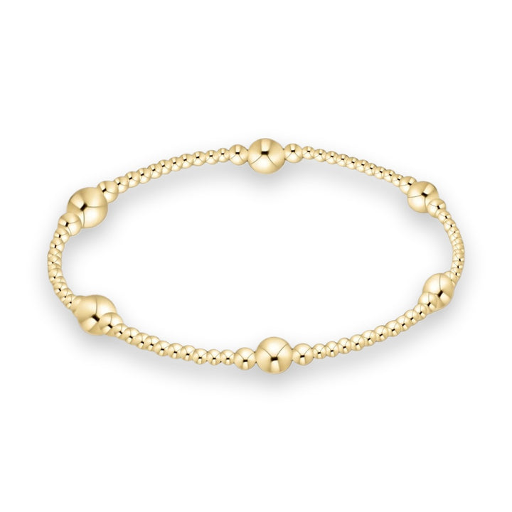 14k gold filled beaded bracelet by Erimish centered on a white background featuring small polished spheres and five larger focal gold beads with a high-shine reflective finish
