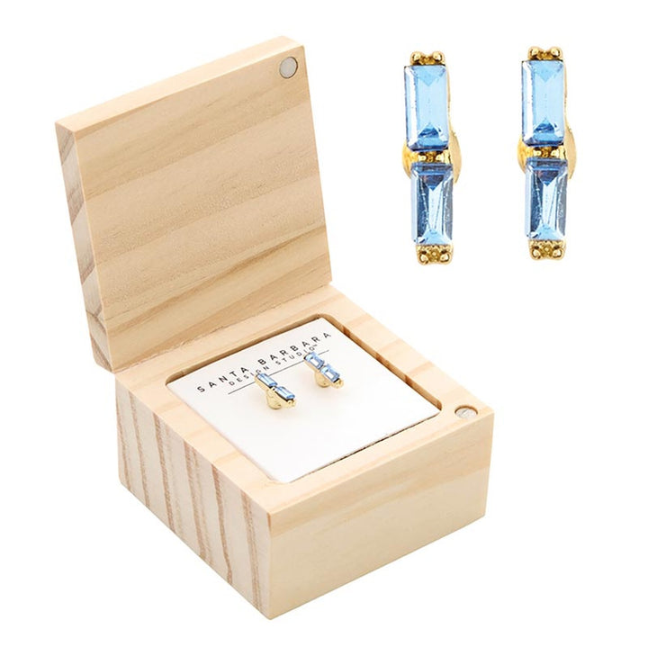 Jewelry by Santa Barbara Design Studio featuring a pair of light blue baguette stud earrings displayed in a natural wood gift box on a white branded card with gold-tone metal settings and stacked rectangular crystals