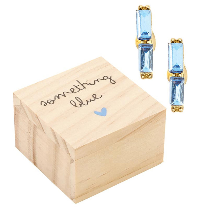Handcrafted jewelry and wooden gift box by Mud Pie featuring light blue baguette-cut crystal earrings with gold-toned metal settings set beside a pine wood box with something blue script and a tiny painted blue heart on a white studio background