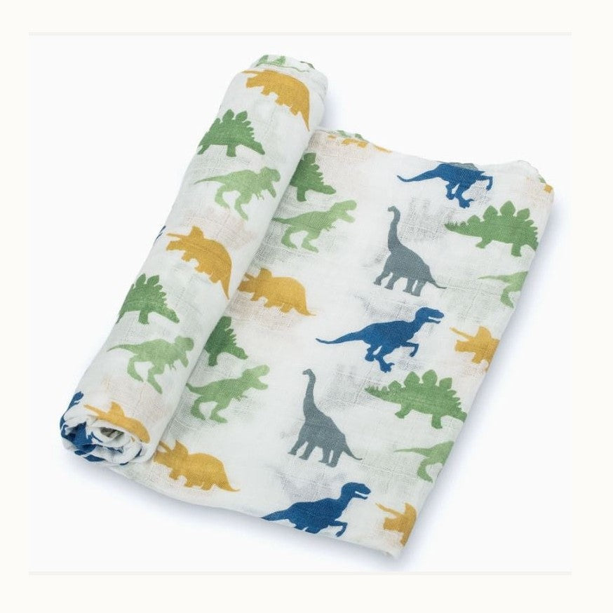 Muslin cotton baby swaddle blanket showcasing a repeat pattern of colorful dinosaur silhouettes including a forest green Stegosaurus, mustard yellow Triceratops, and navy blue Tyrannosaurus Rex against a crisp white background
