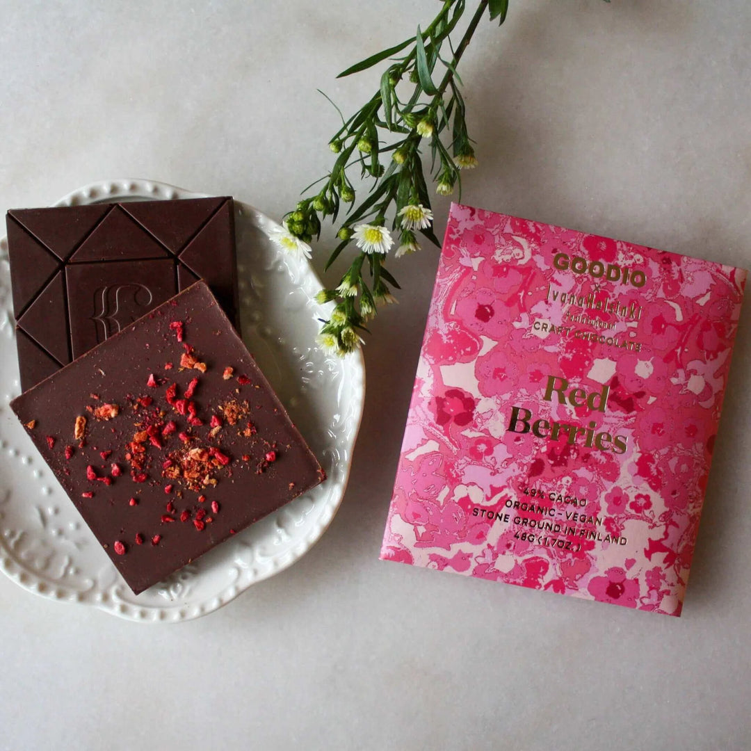 Goodio Red Berries chocolate bar beside chocolate squares topped with dried berries on a white plate