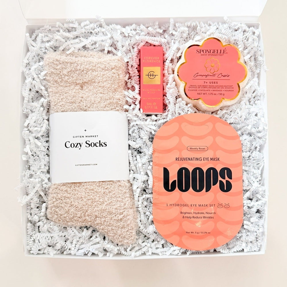 Gift set with socks, parfume, and sponge buffer in a decorative box on a white background
