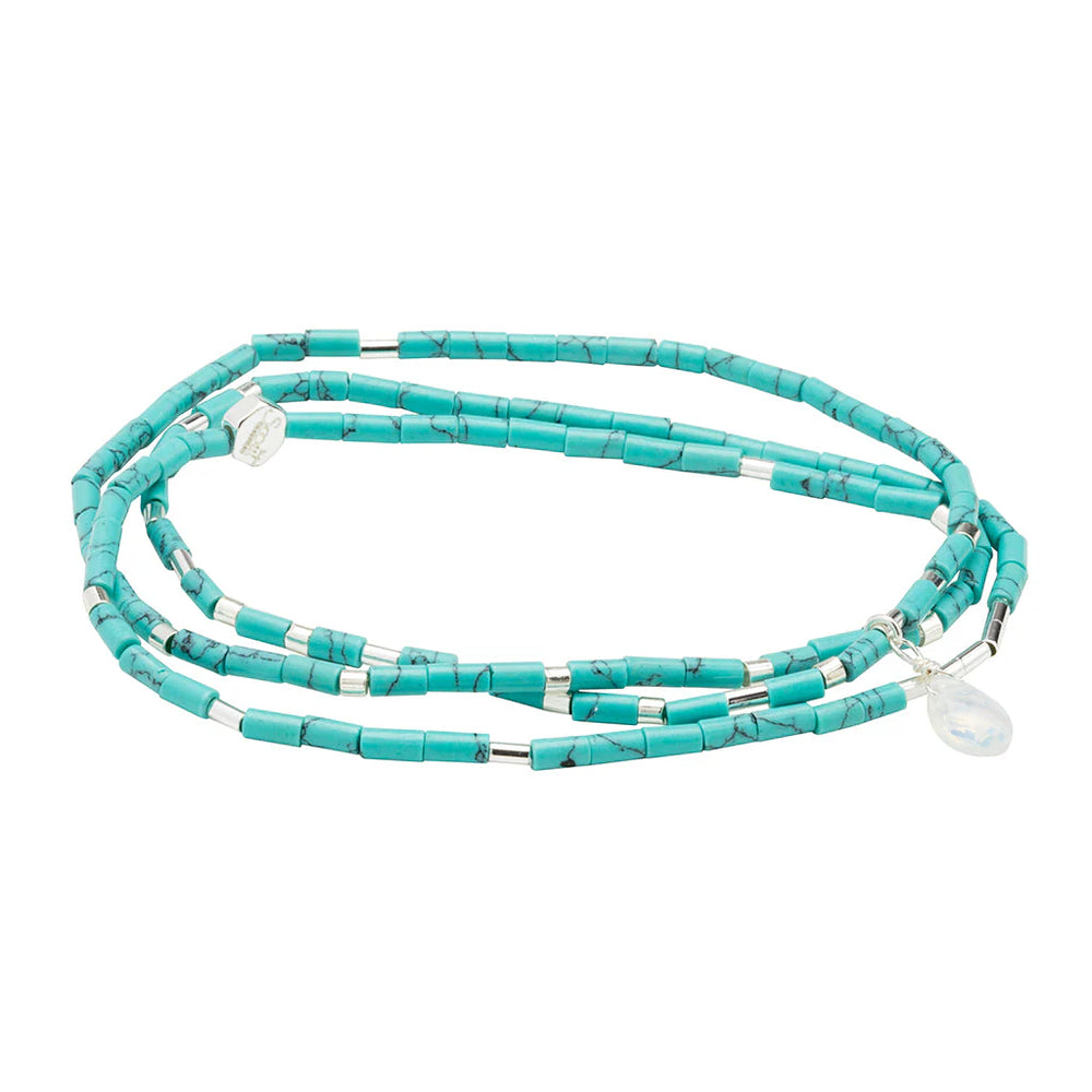 Handcrafted jewelry by Scout Curated Wears featuring a triple-wrap bracelet of cylindrical turquoise beads with dark veining, intermittent silver metallic spacers, and a faceted iridescent moonstone charm on a white background