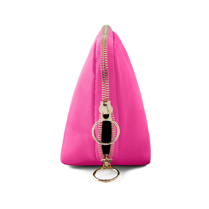 Studio photograph of a vibrant fuchsia triangular nylon cosmetic pouch on a white background featuring a polished gold-tone zipper and two oversized circular ring pull tabs
