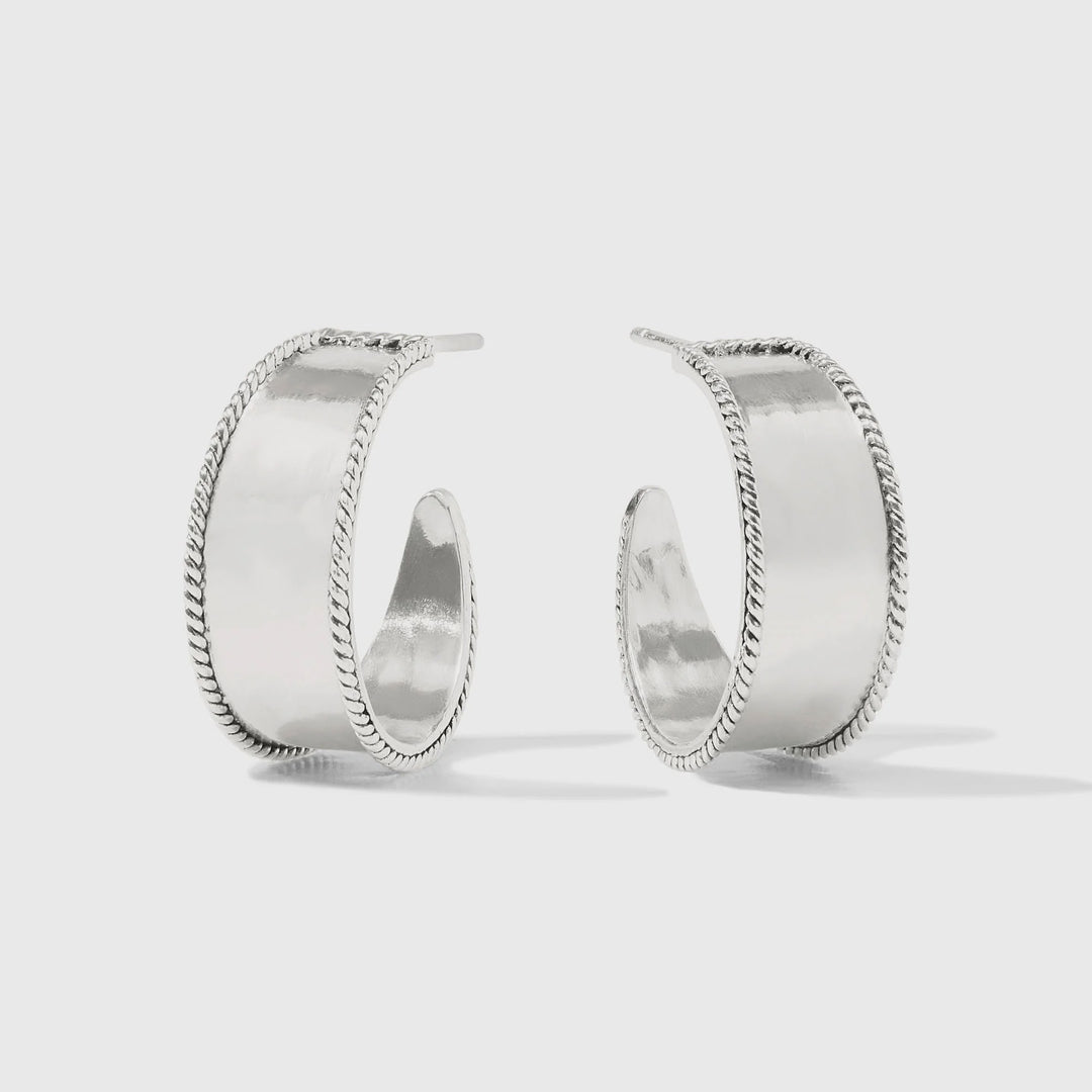 Sterling silver jewelry showcasing a pair of wide, open-back hoop earrings with high-polished central bands and intricate braided rope edges on a minimalist gray background