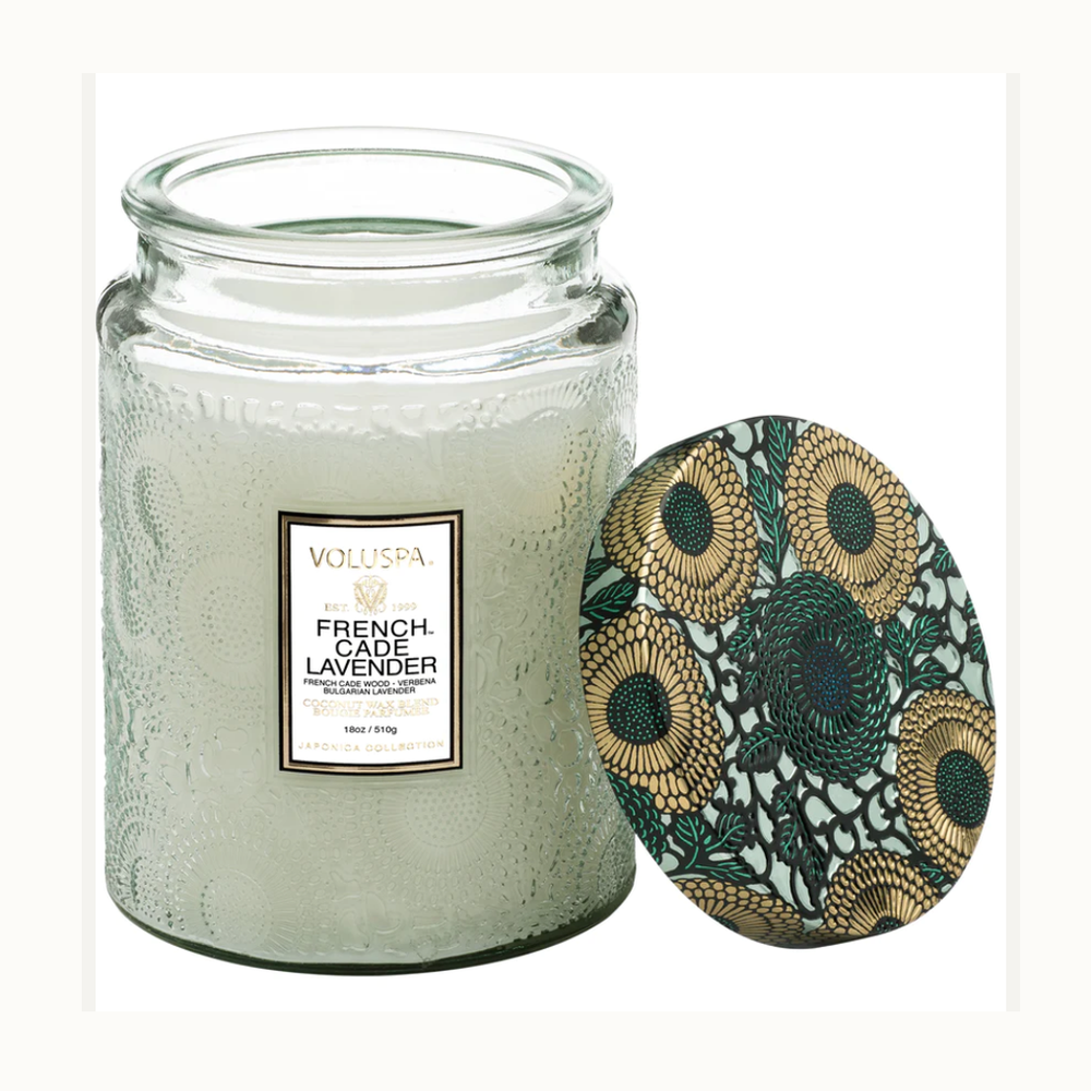 Scented glass jar candle by Voluspa featuring the French Cade Lavender fragrance from the Japonica Collection on a white background, showcasing an intricate embossed floral texture and a decorative lid with metallic gold and teal botanical patterns
