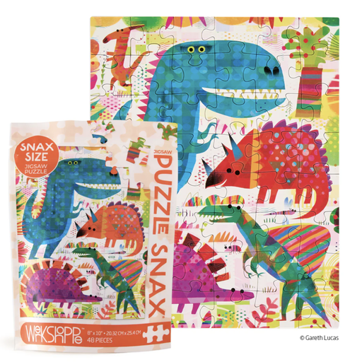 Jigsaw puzzle by Gareth Lucas depicts a vibrant prehistoric landscape with a large blue polka-dot Tyrannosaurus Rex, a red geometric Triceratops, and colorful abstract trees shown next to its 48-piece Snax size packaging