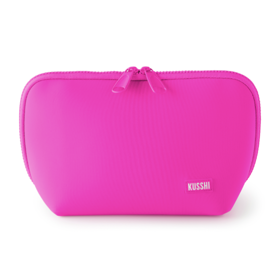 Studio product photograph of a Kusshi brand vibrant magenta makeup bag on a white background featuring a dual-pull zipper, rounded corners, and a small woven logo label